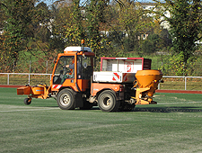 Kleinfahrzeug der Sportflächenpflege befährt Kunstrasenplatz